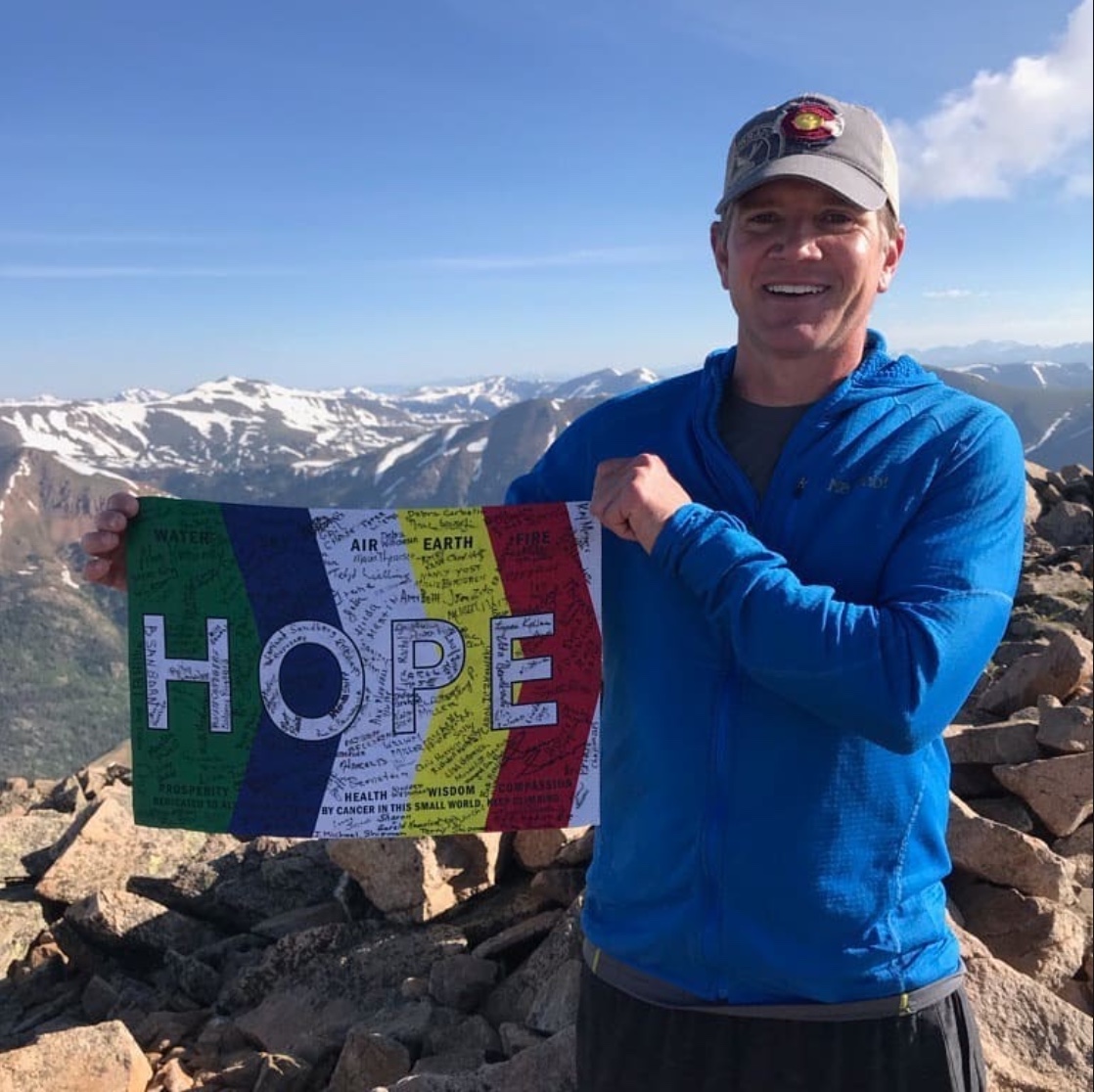 Sean Swarner on a summit holding the HOPE Flag