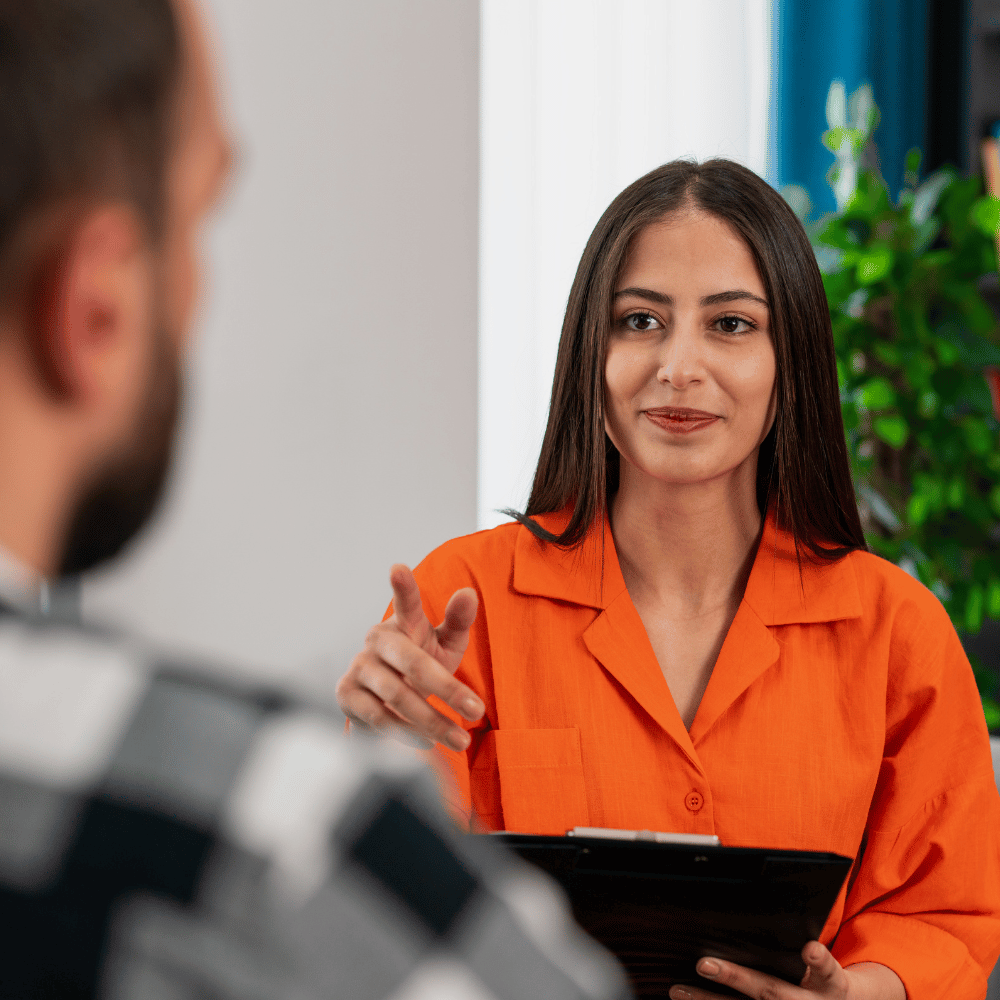 A woman with a clipboard talking talking to a man