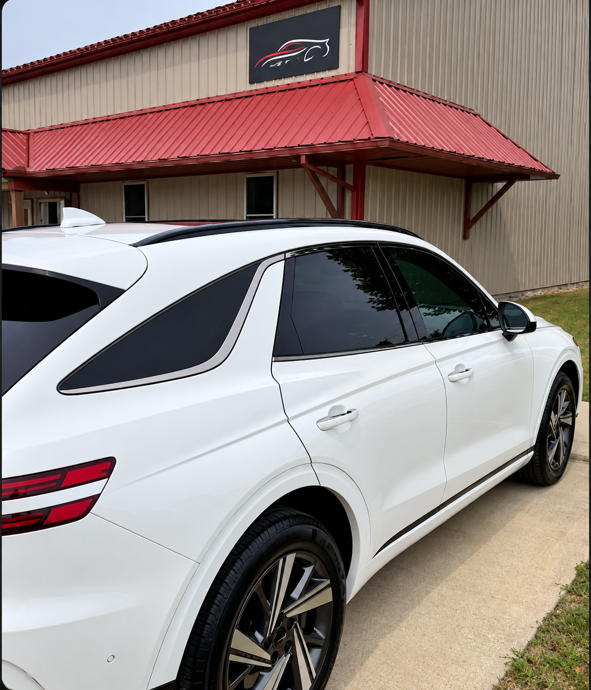 Finished white vehicle with dark tinted windows outside Nip Tuck Auto