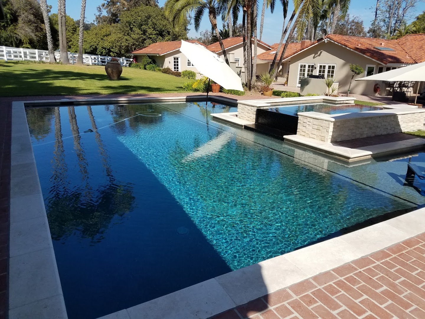 Vanishing-edge pool with raised spa and travertine coping