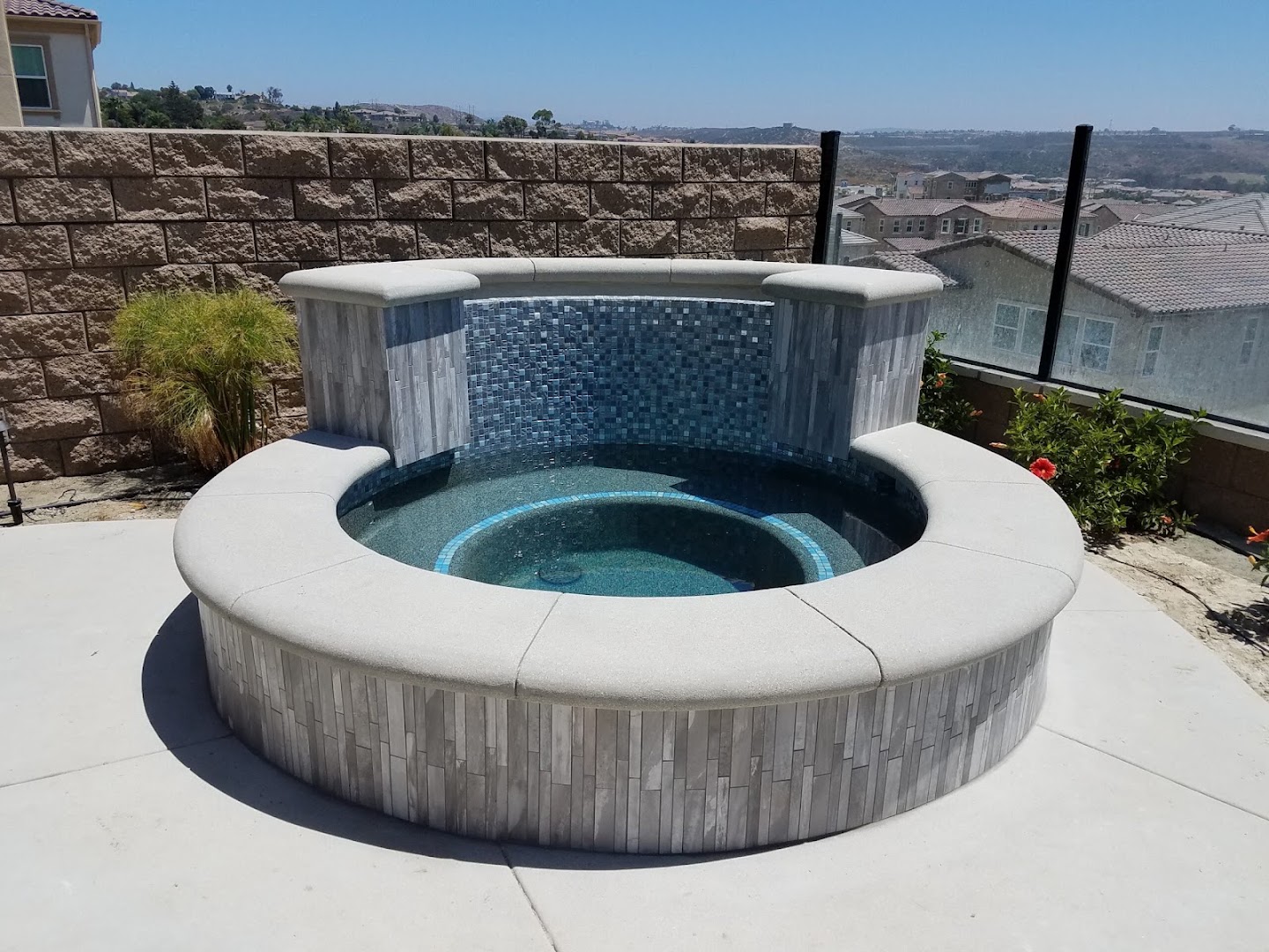 Round spa with glass tile water wall and new coping