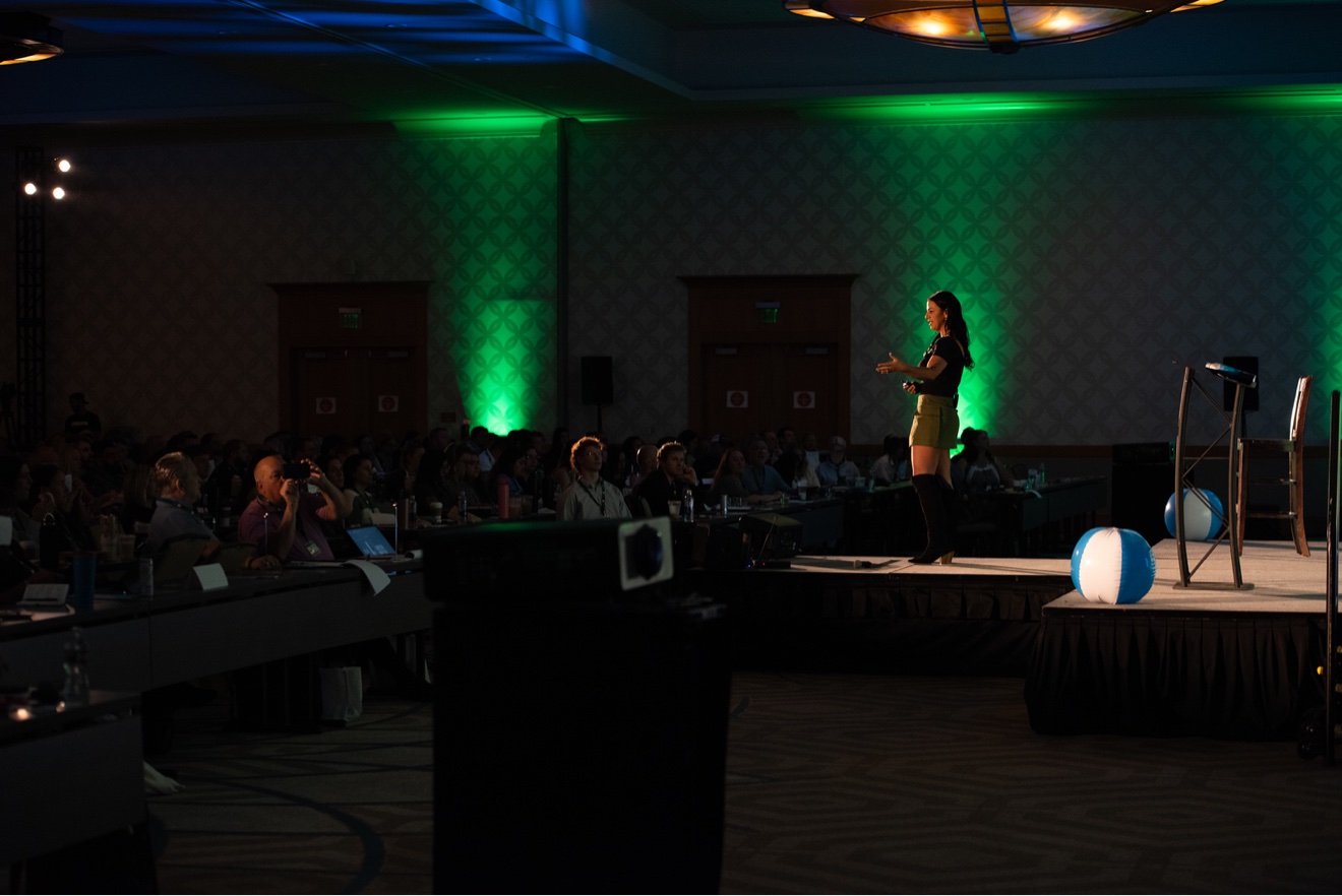 Dr. Elise Rigney speaking on stage to a packed room