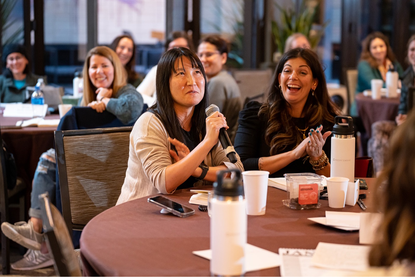 ChiroIntensive member sharing while the room applauds