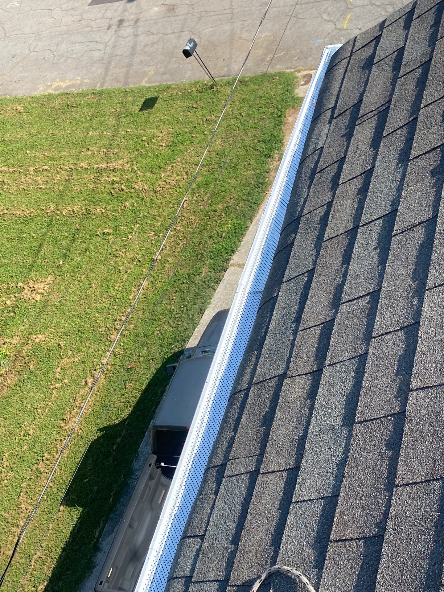New white gutter guard running the full length of a roofline above a front lawn