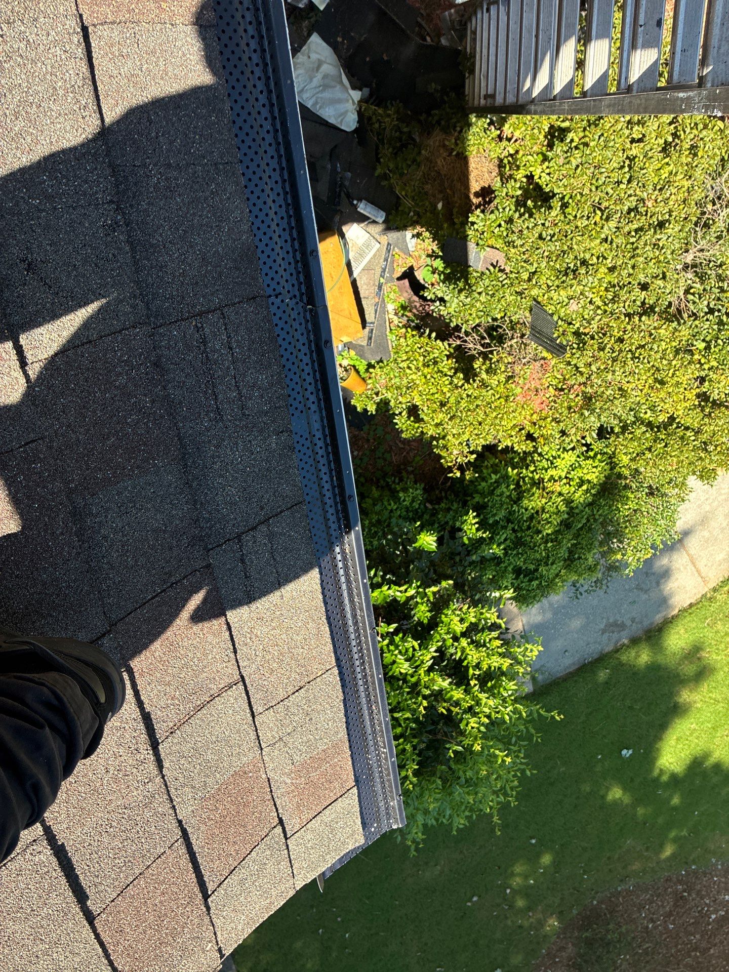Technician's shadow at the roof edge where a black guard section meets a silver one