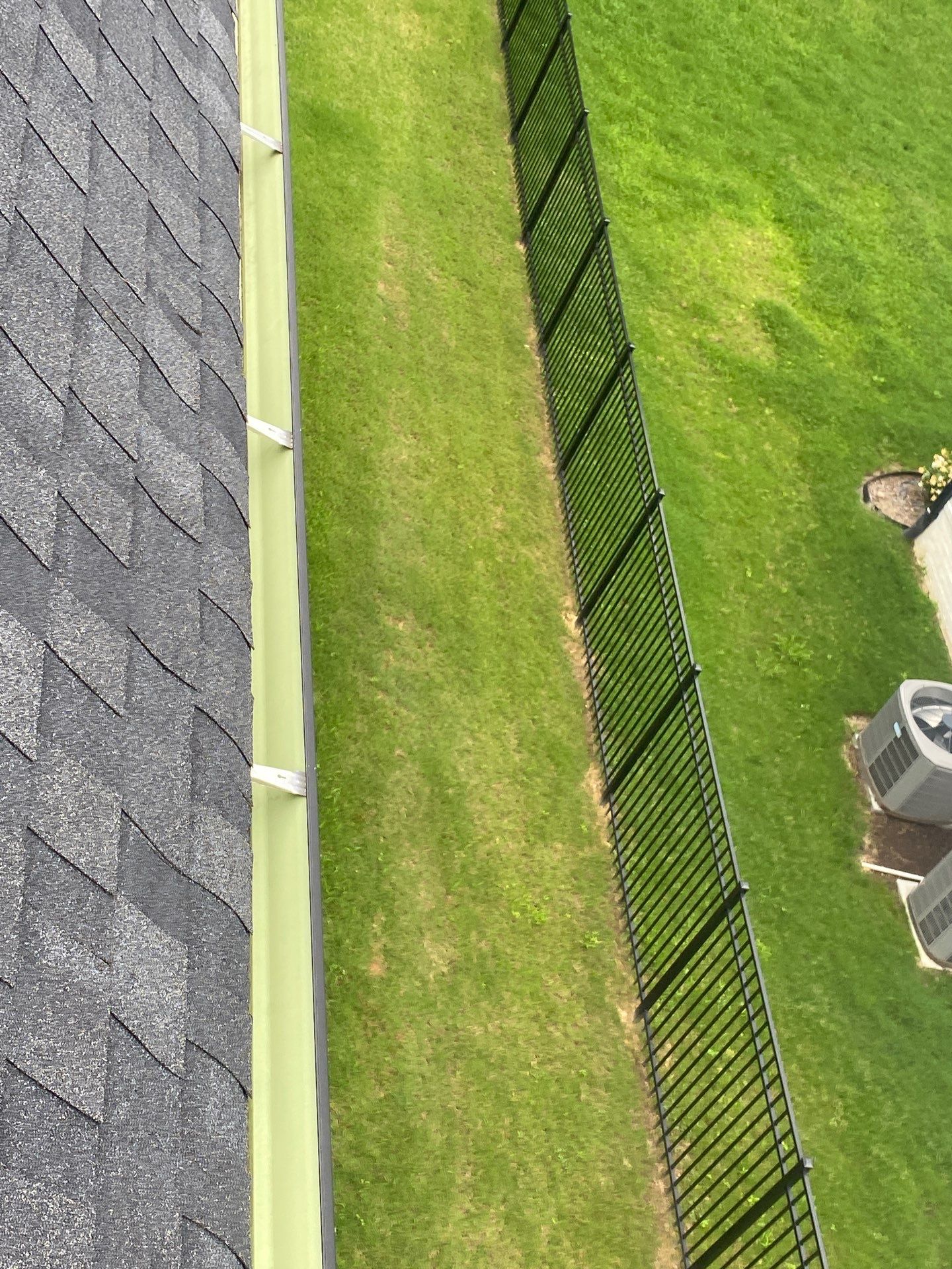 Clean gutter run along a shingle roof edge above a mown back lawn