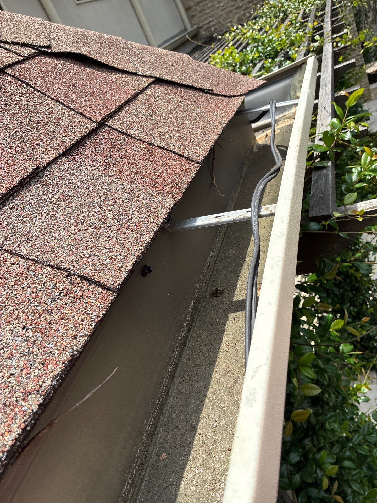 Gutter pulling away from the fascia at a roof valley with the hanger exposed