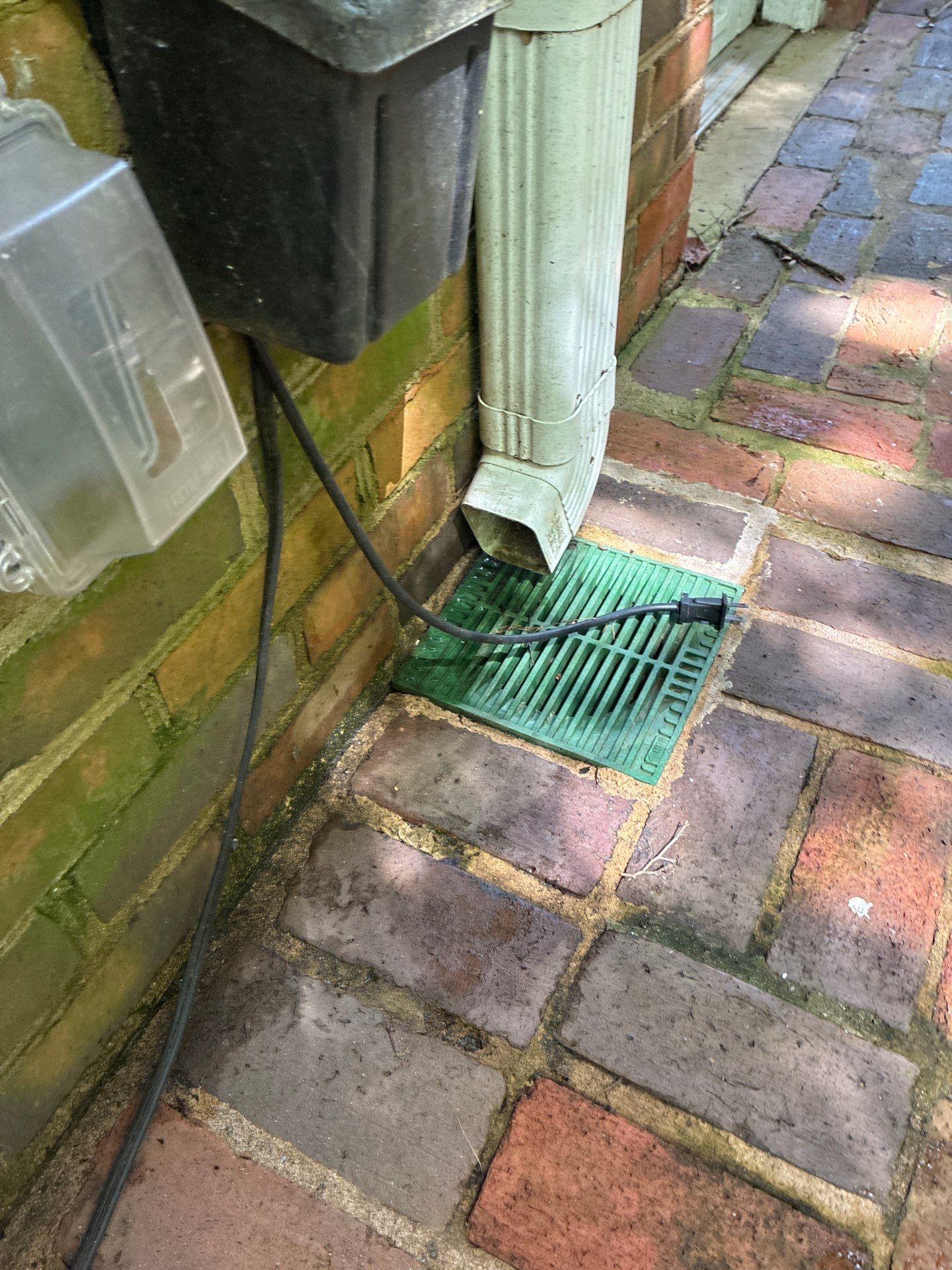 Downspout elbow directing water into a drainage grate at ground level