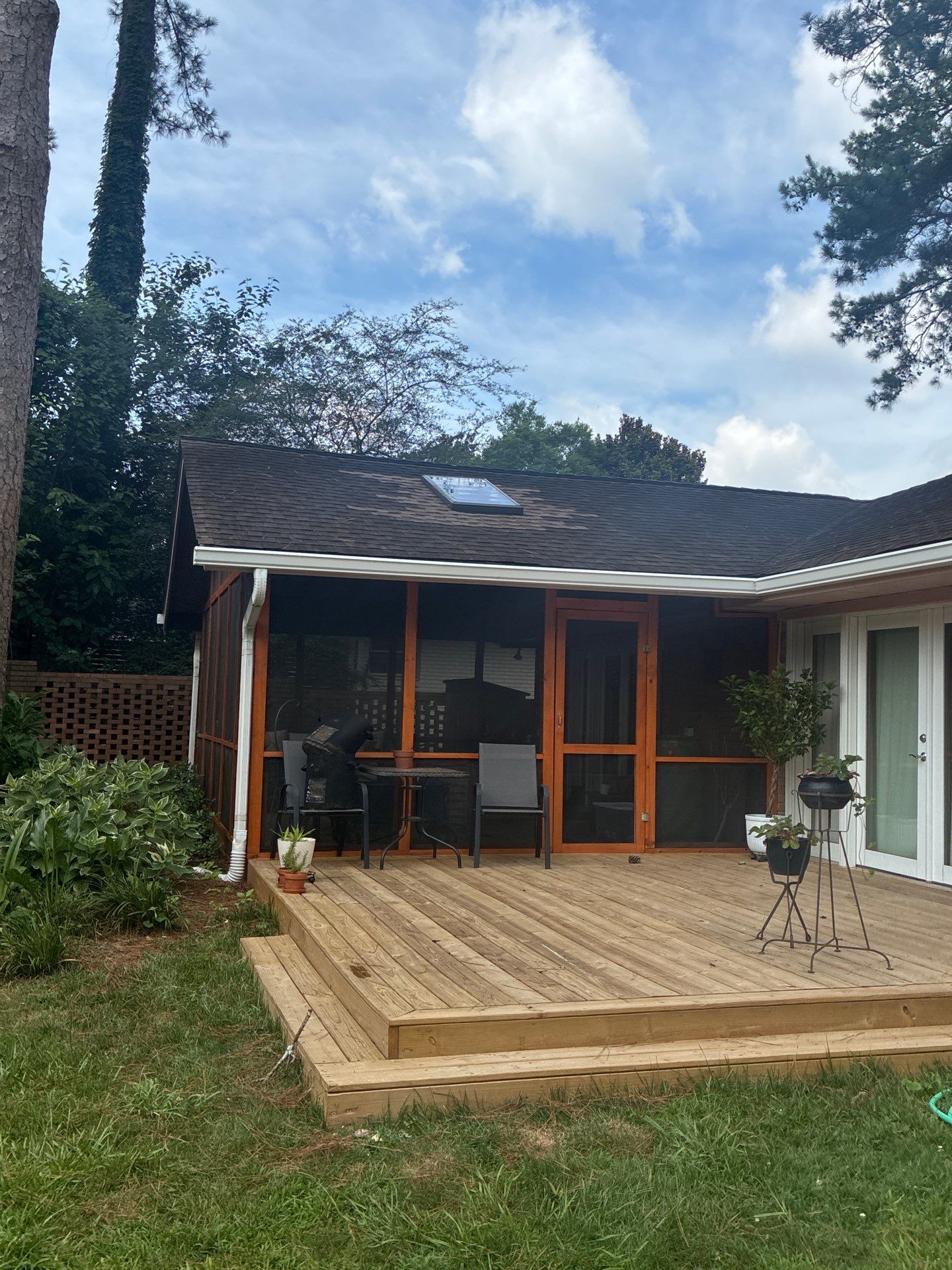 Screened back porch with a downspout running down to grade