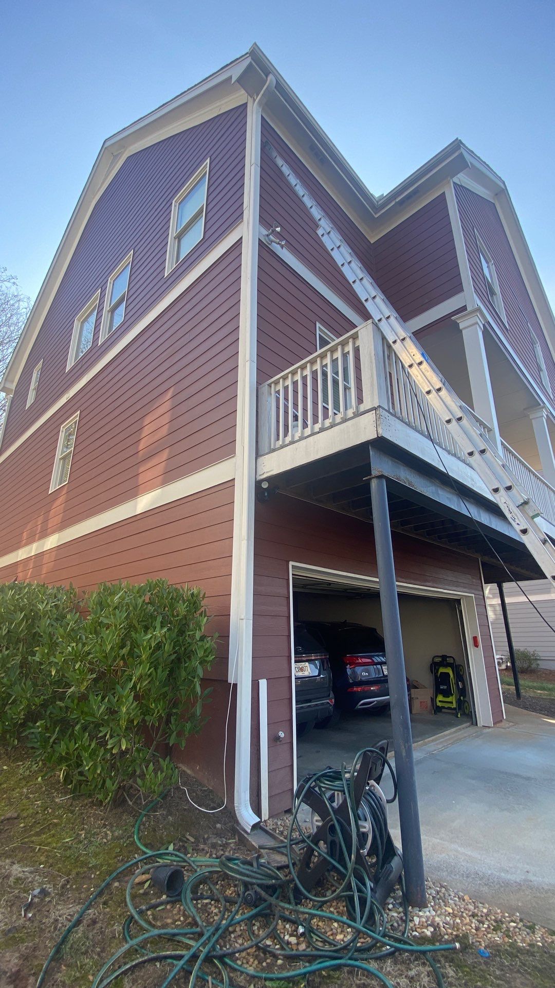 Two-story home with a ladder reaching a downspout running the full height of the wall