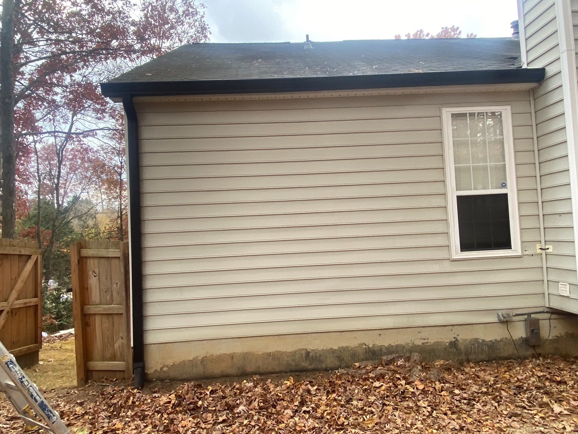 Dark staining at the foundation directly below a downspout discharge