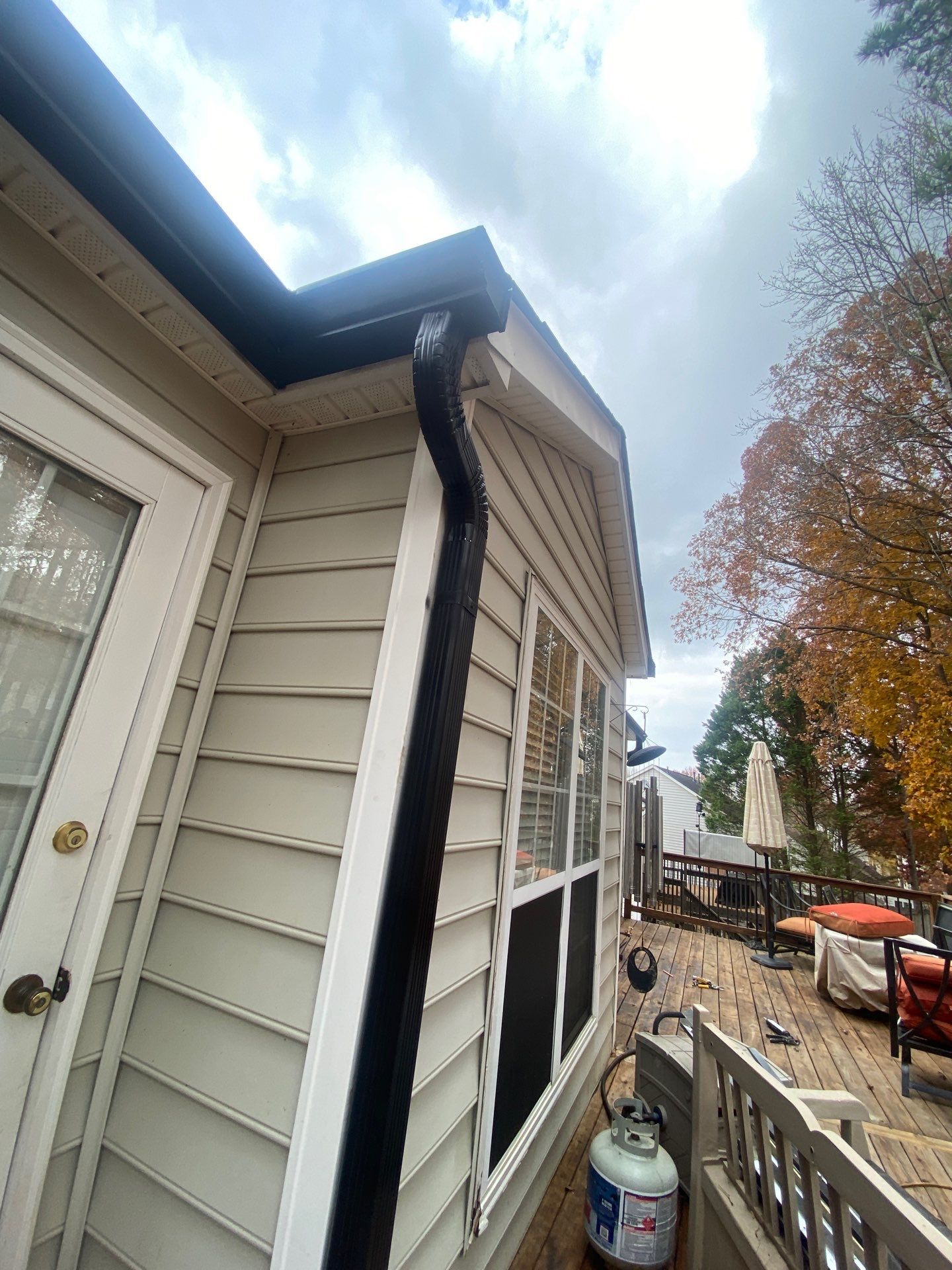 Flexible downspout extension section at the corner of a deck