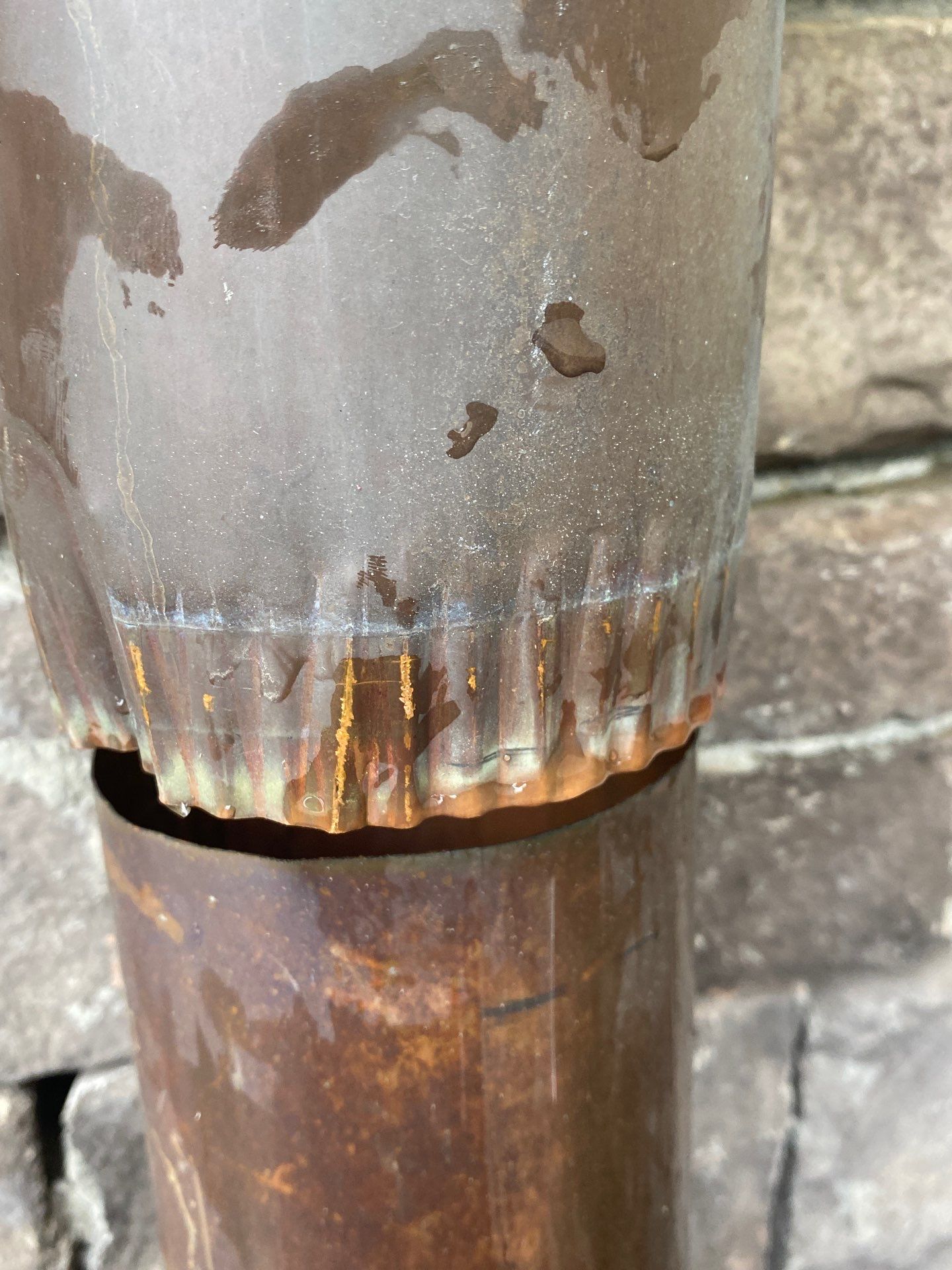 Rusted downspout section at ground level