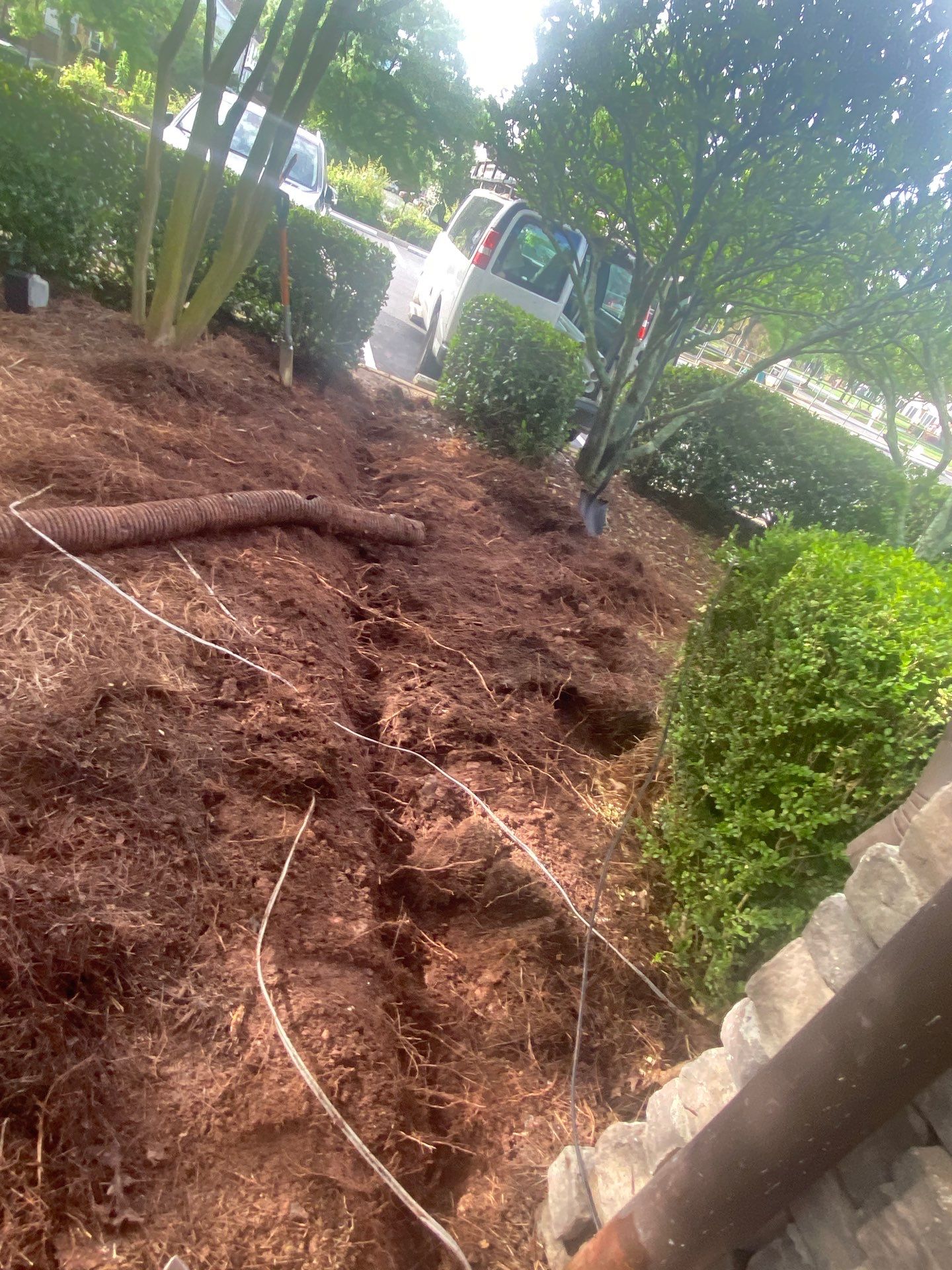 Trench dug through red clay along a planting bed