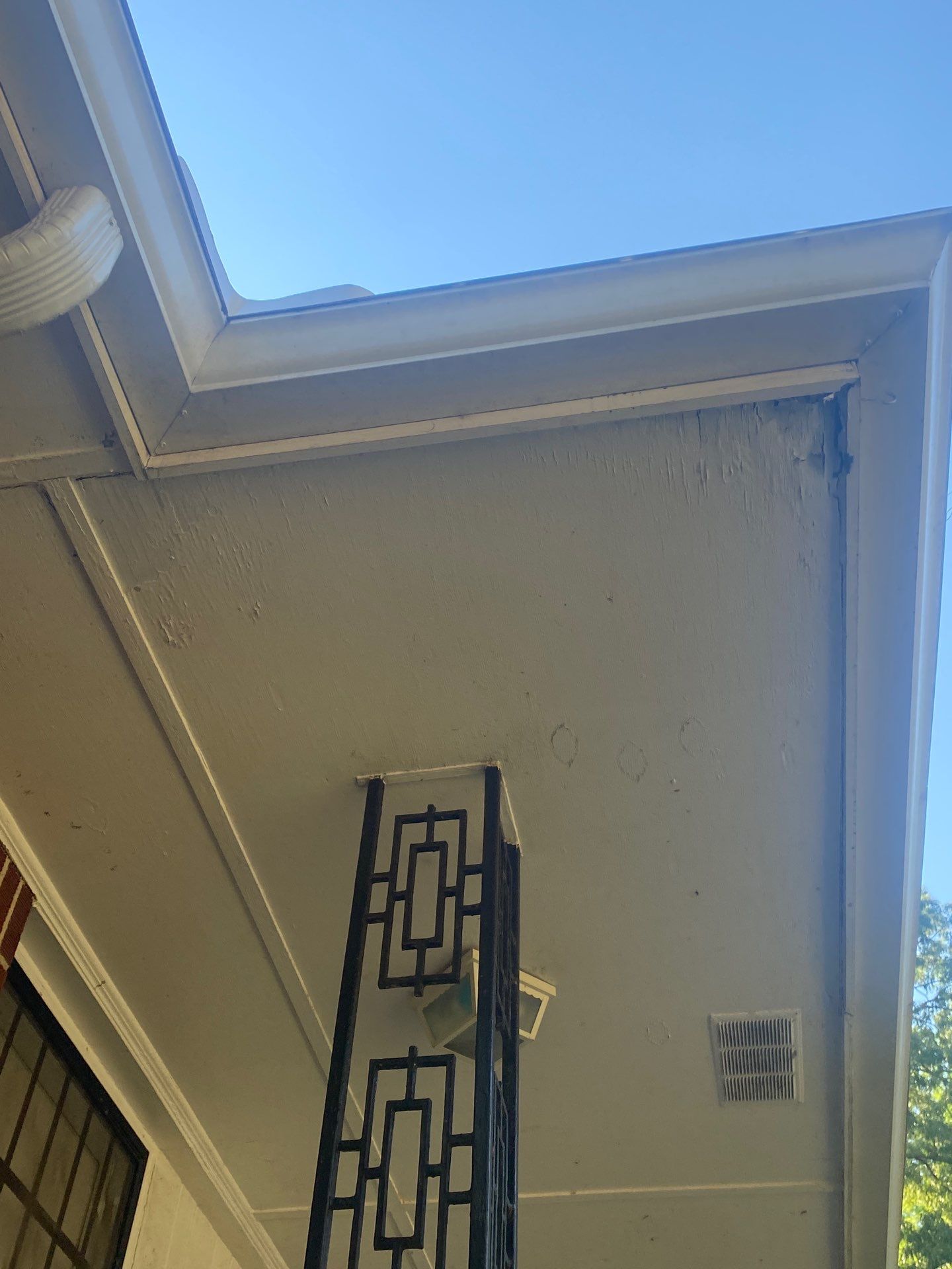 Soffit and fascia under the roofline of an older home with a vent and light fixture