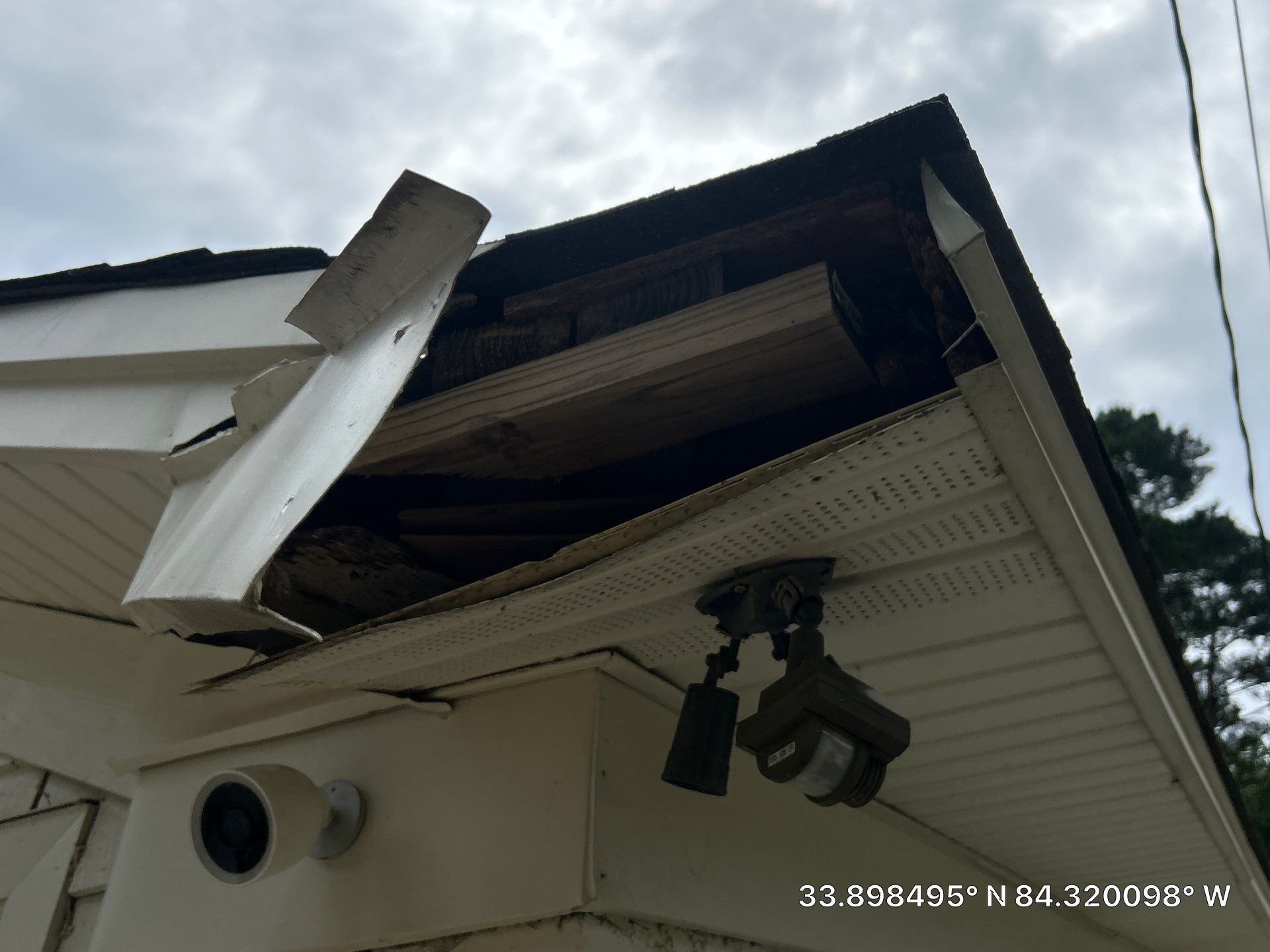 Fascia board torn open exposing rotted wood along the roof edge