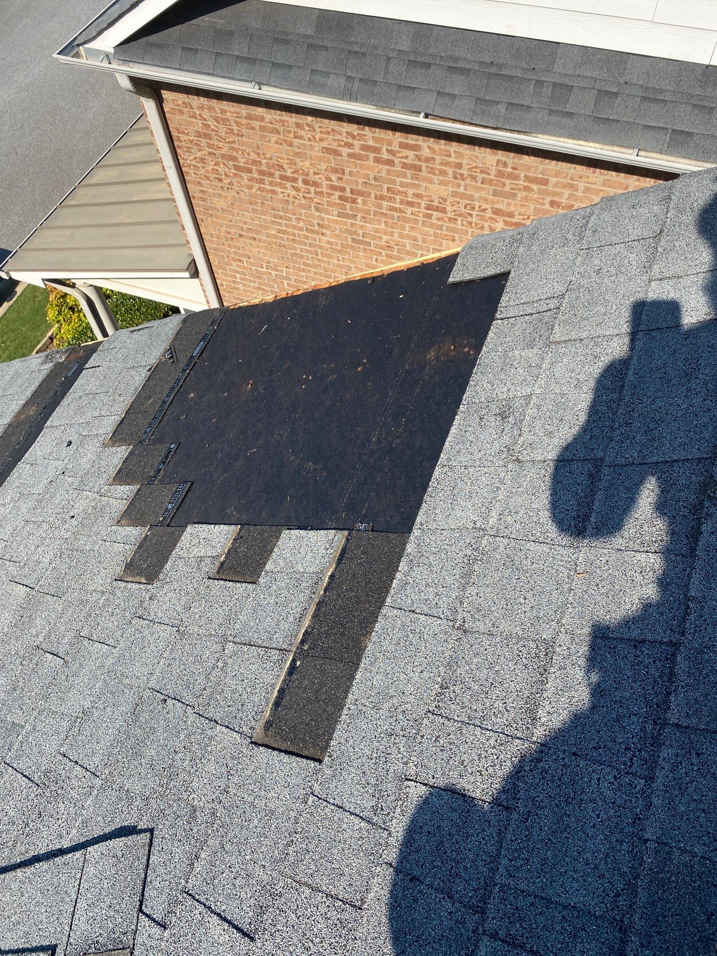 Aerial view of a shingle replacement mid-project, damaged section pulled and new underlayment exposed
