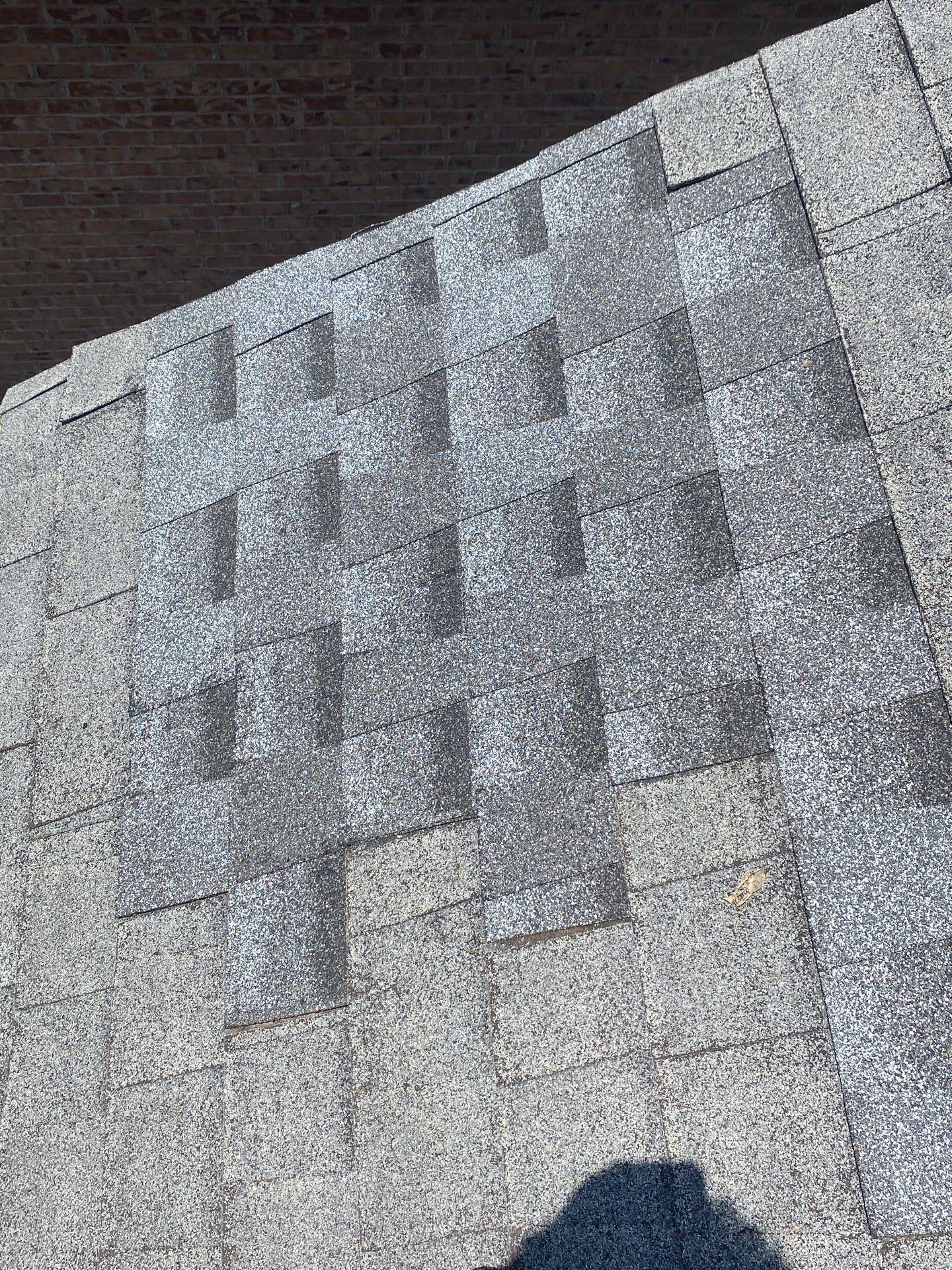 Close-up of curled, worn asphalt shingle tabs along a roof edge