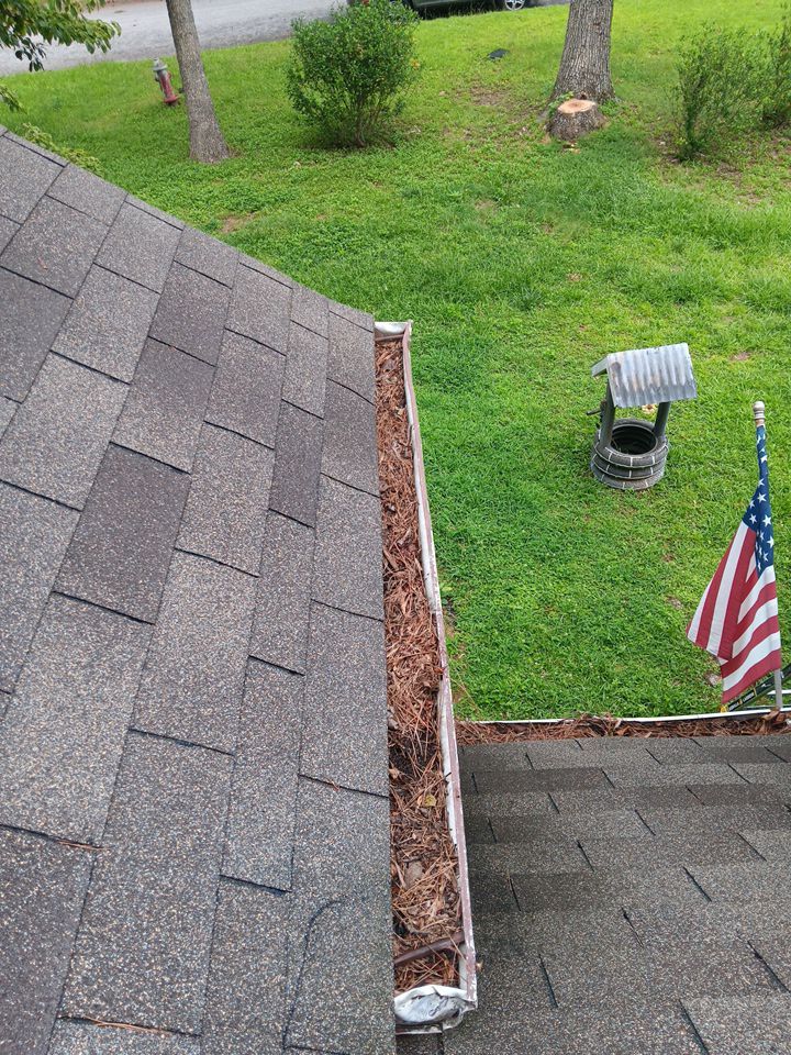 Clean gutter run along a shingle roof above a mowed lawn