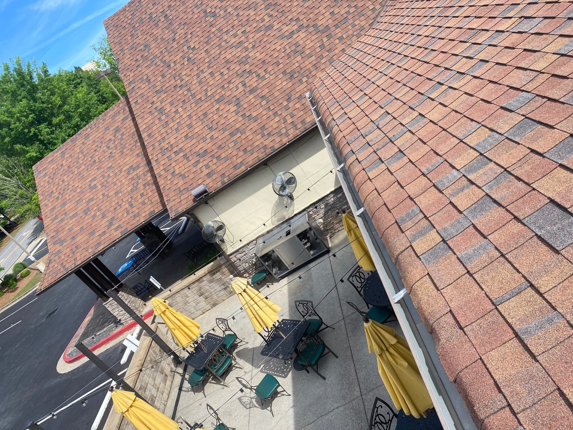 Gutter run along a commercial roof above a restaurant patio and parking lot