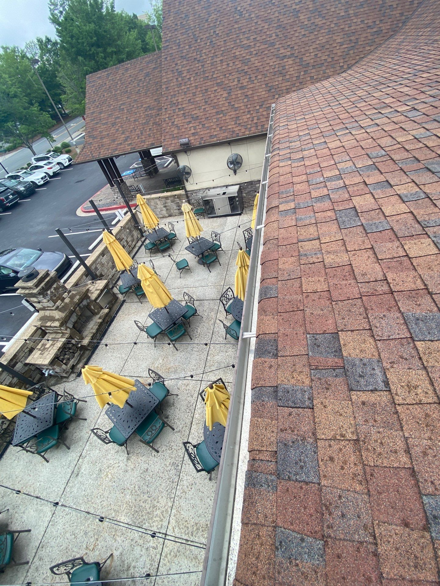 Roof edge of a commercial building above an outdoor patio with umbrellas