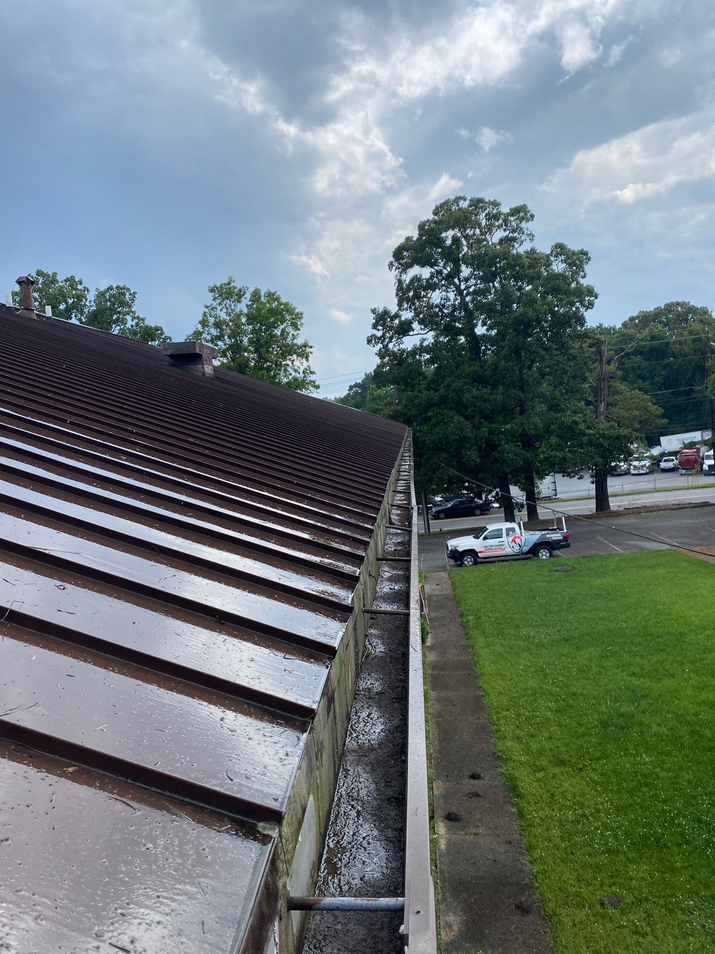 Wet commercial gutter run along a metal roof edge after a flush