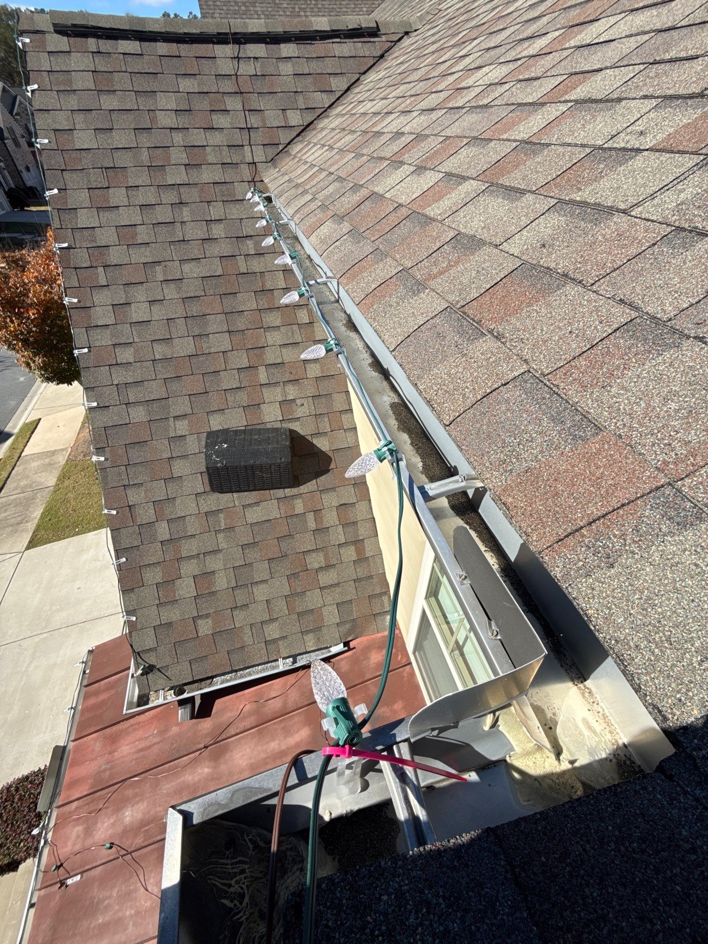 String of holiday lights clipped along a gutter on a shingle roof