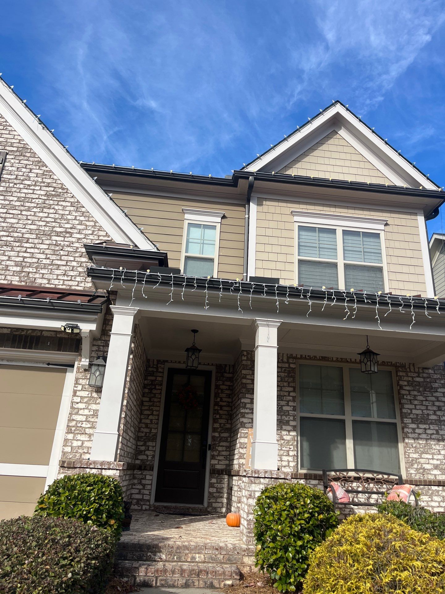 Two-story home with a covered porch and lights run along the full roofline