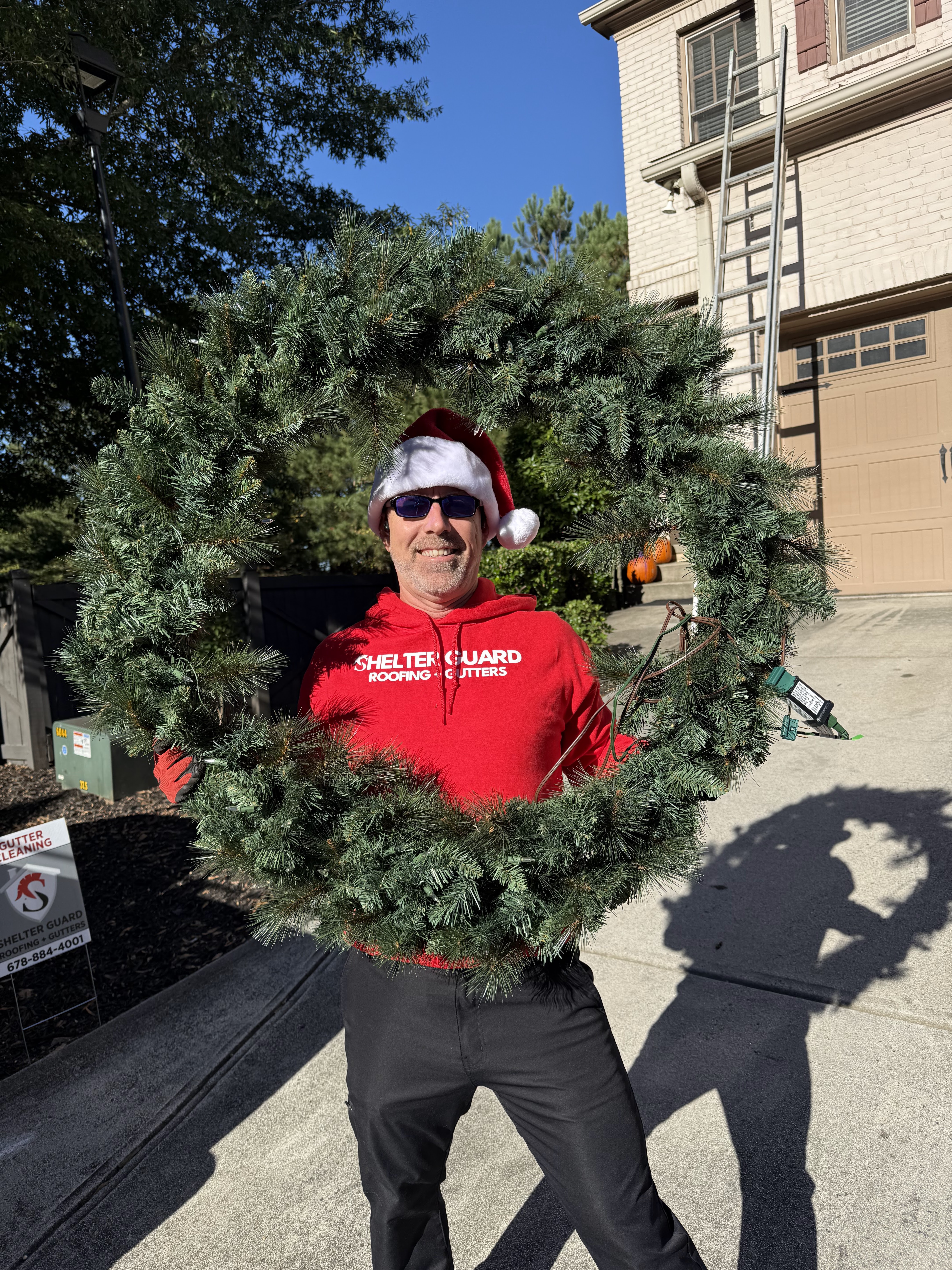 Crew member in a Santa hat holding a finished wreath before hanging it