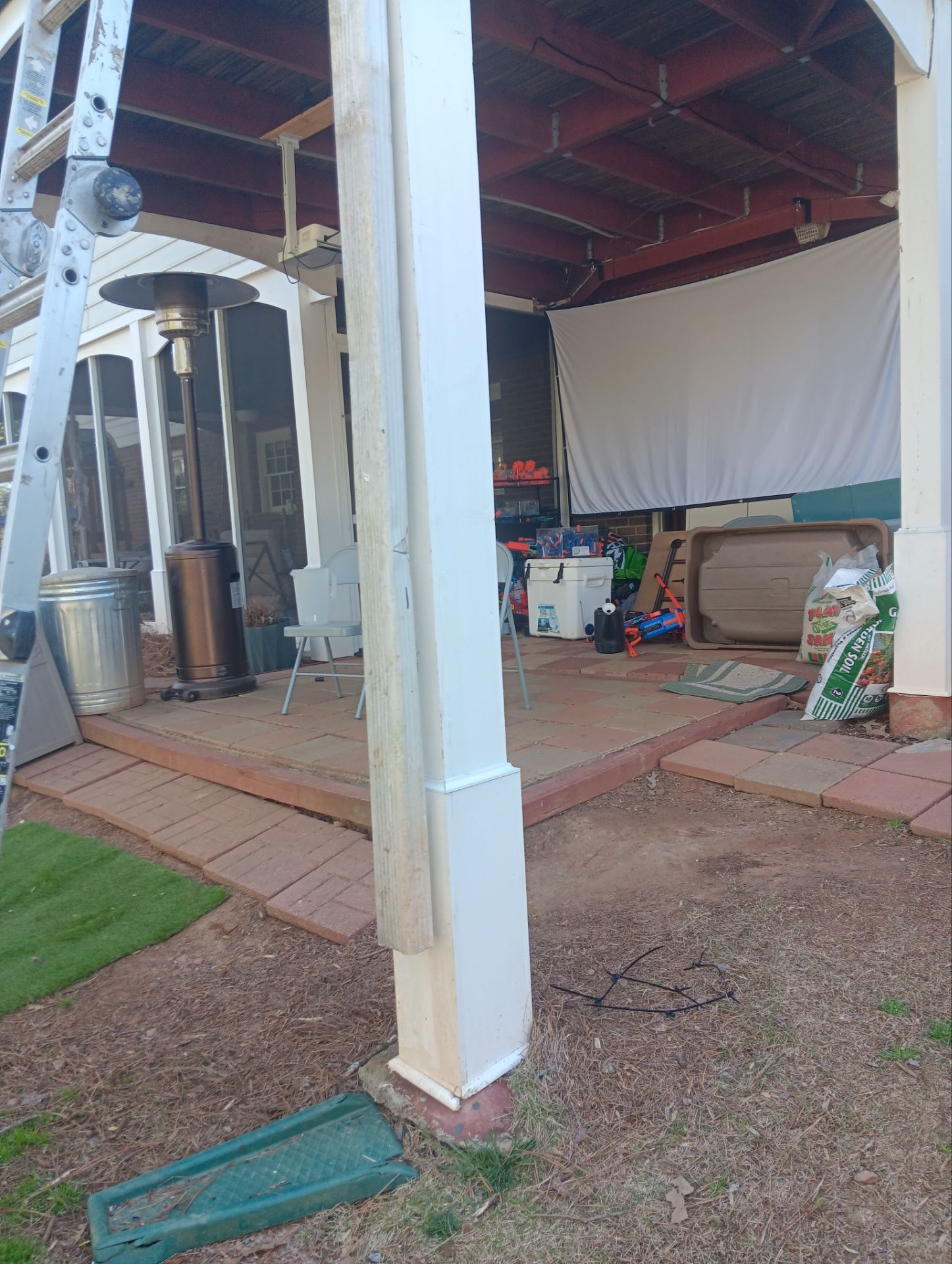 White porch column and paver patio under a covered deck