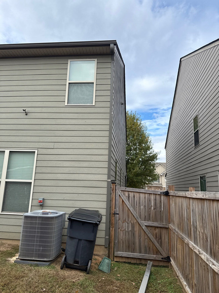 Side yard of a two-story home with the downspout beside an AC unit