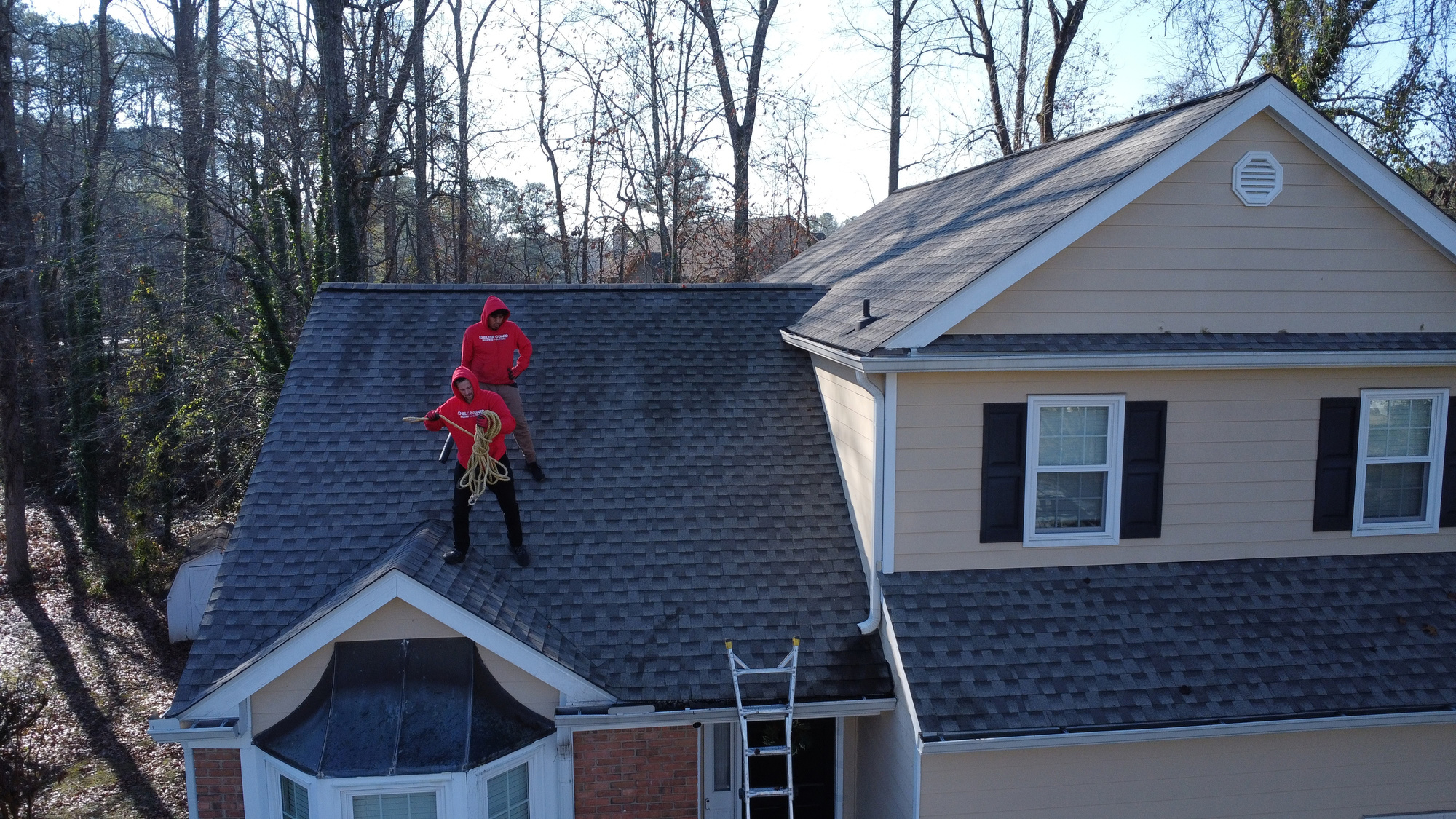 Shelter Guard tech working on the roof of a two-story home