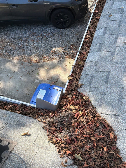 Debris scooped out of a gutter onto the driveway below