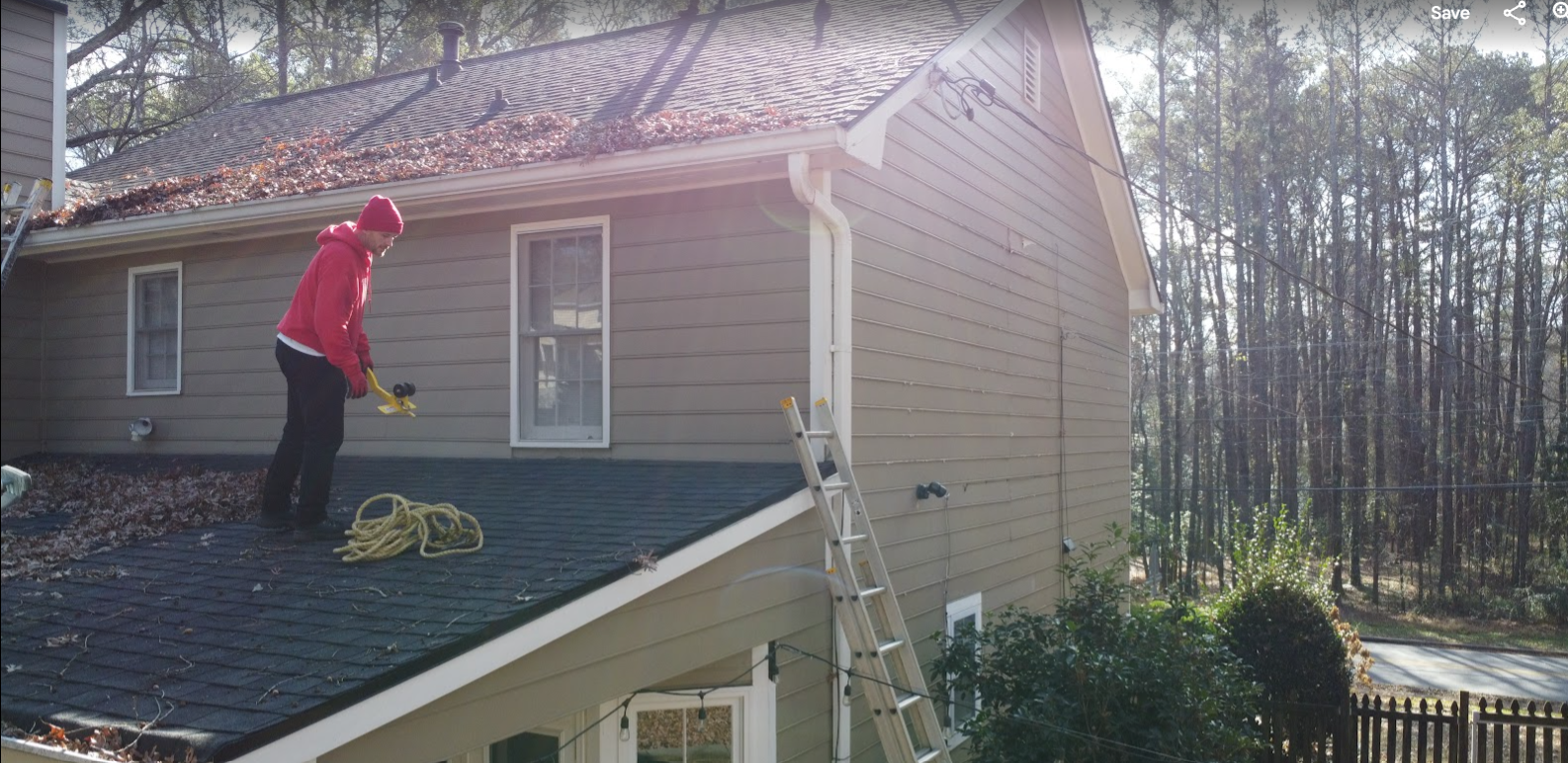 Shelter Guard tech on a roof above a two-story home