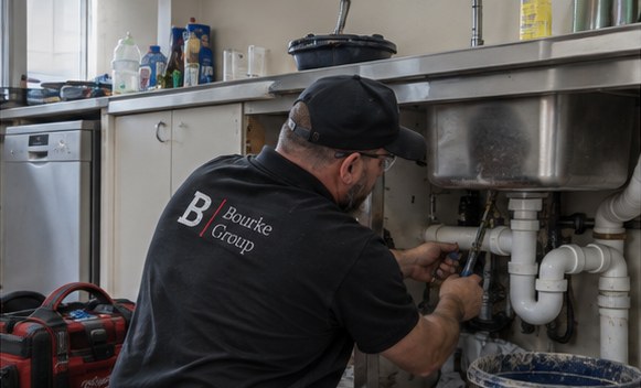 Plumber repairing pipework under a sink