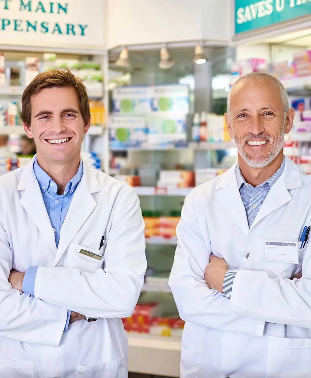Two smiling pharmacists in white coats in a dispensary