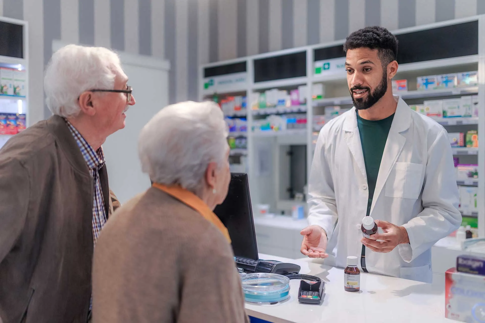 A pharmacist explains a prescription to an older couple at the counter