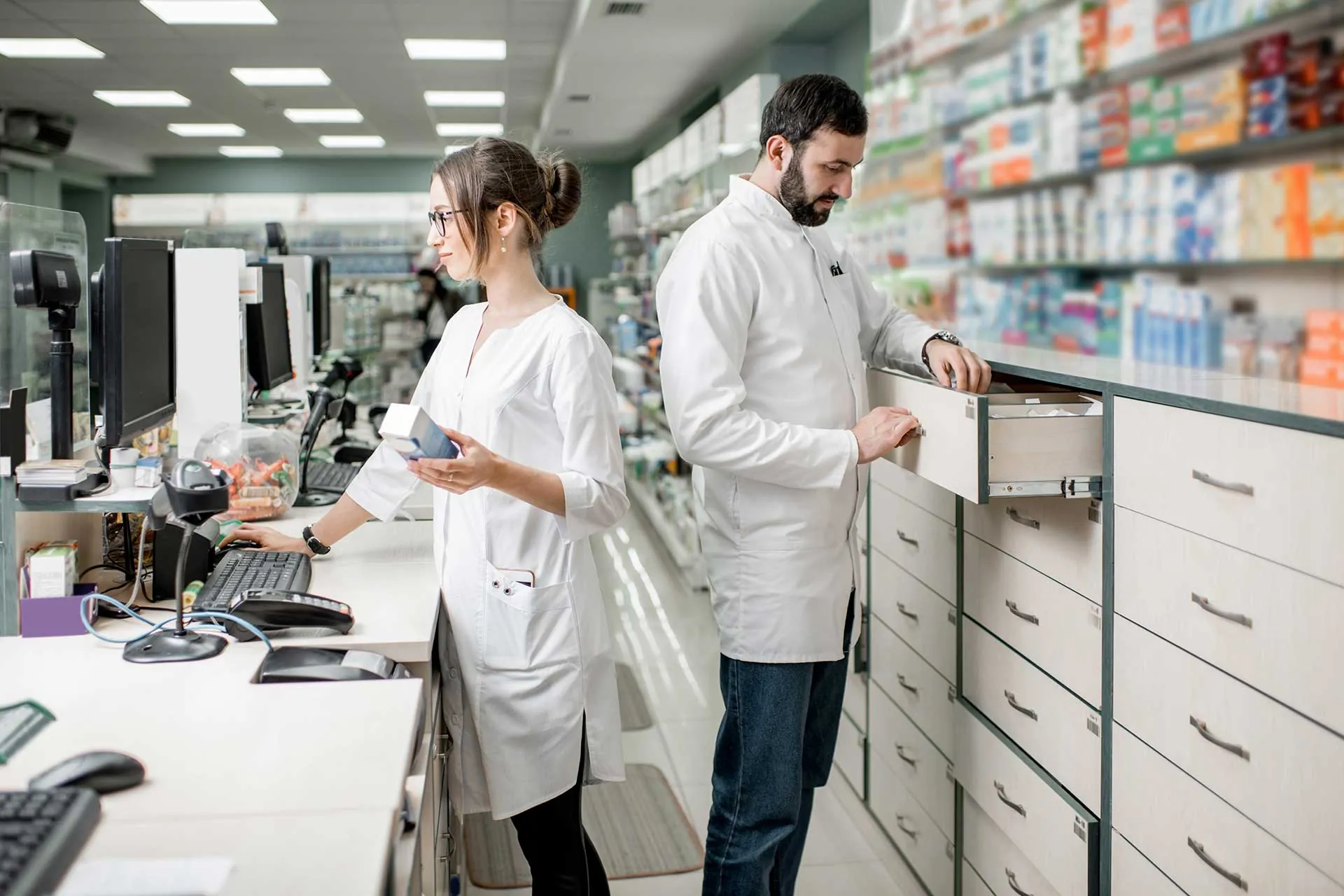 Two pharmacists working together in a pharmacy aisle