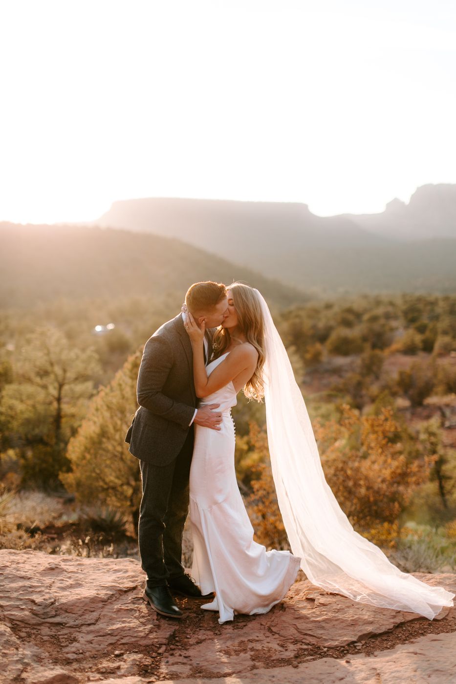 A couple walking hand in hand along a red rock ridge in Sedona at sunset