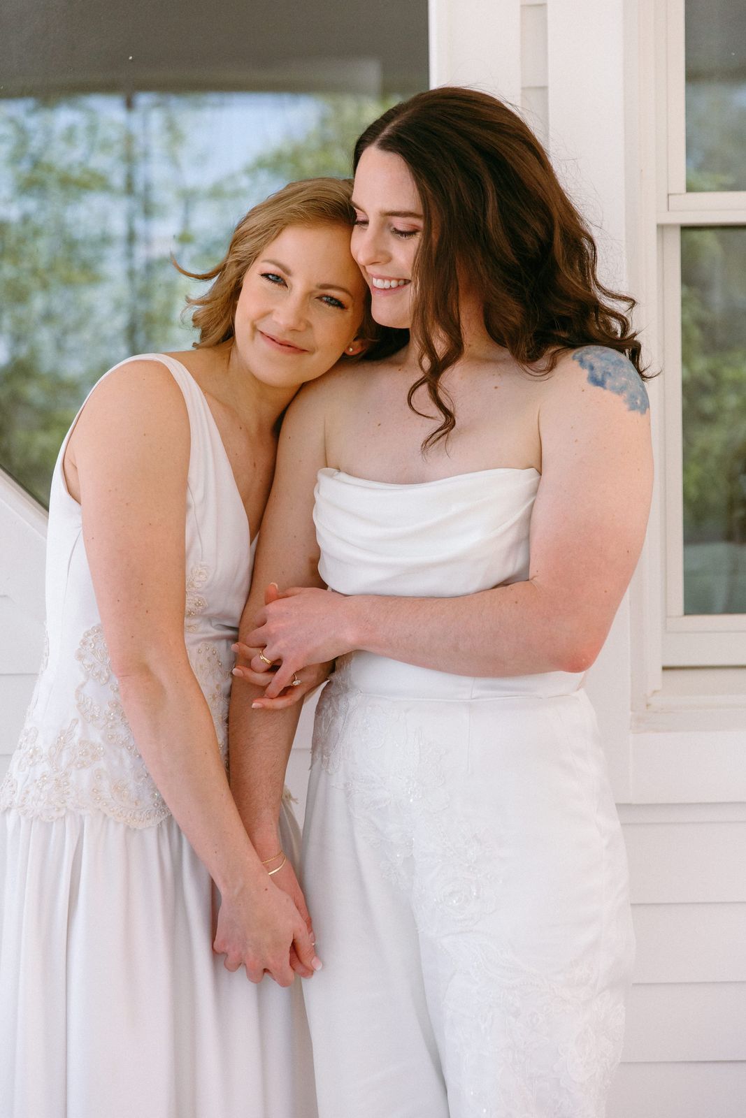 Two brides holding each other close on a porch