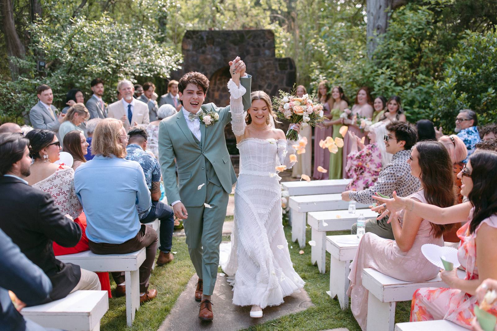 Newlyweds cheering down a garden aisle as guests celebrate
