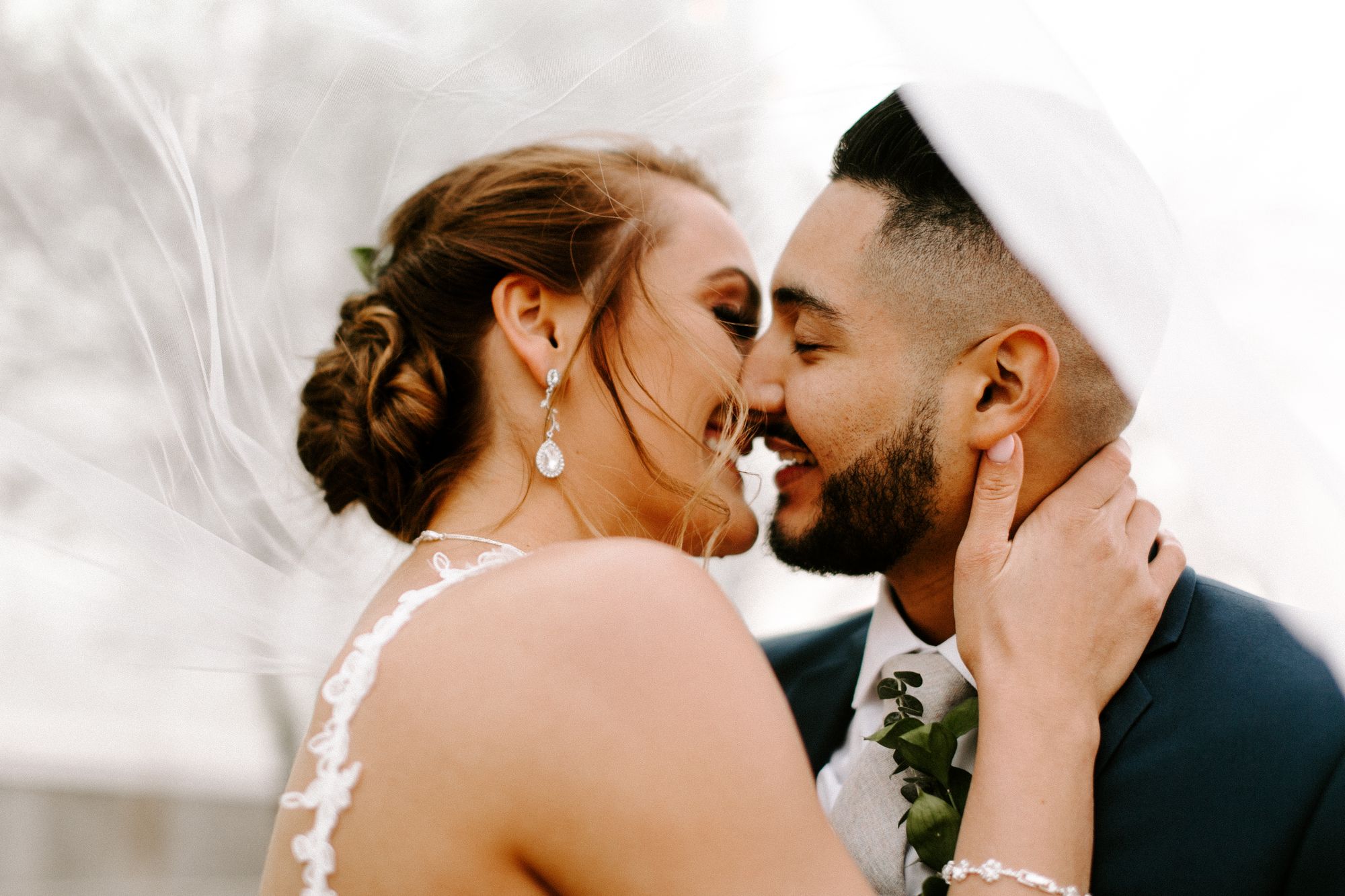 A bride and groom leaning in for a kiss under her veil