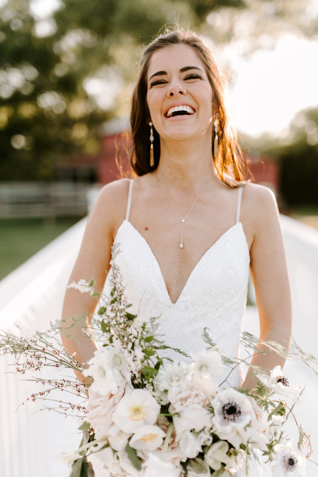 A bride laughing with her bouquet in golden light