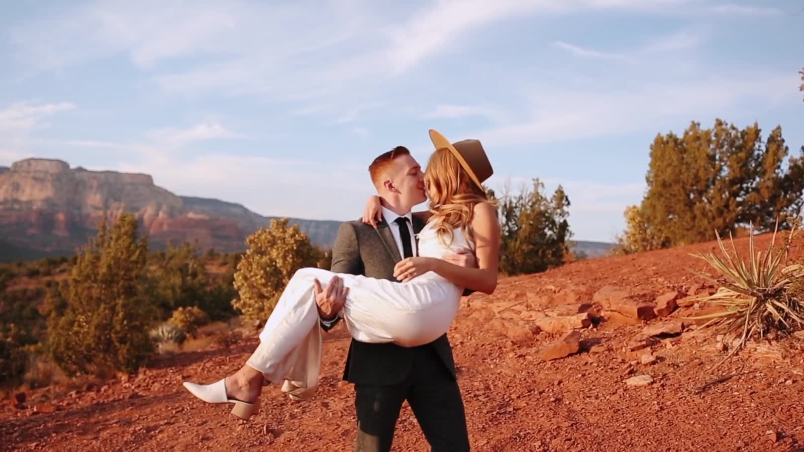 A groom carrying his bride across the red rocks of Sedona