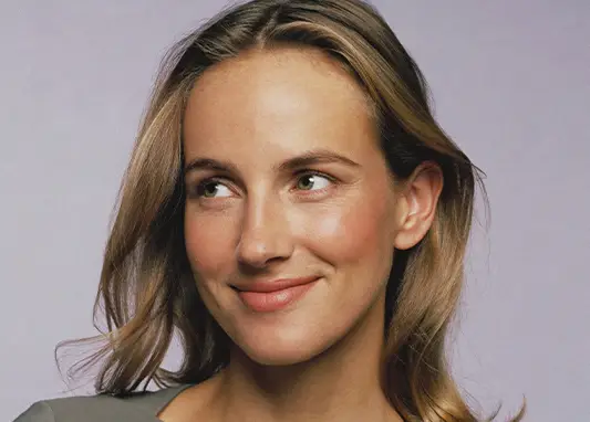 A woman with long hair smiles warmly, showcasing her joyful expression.