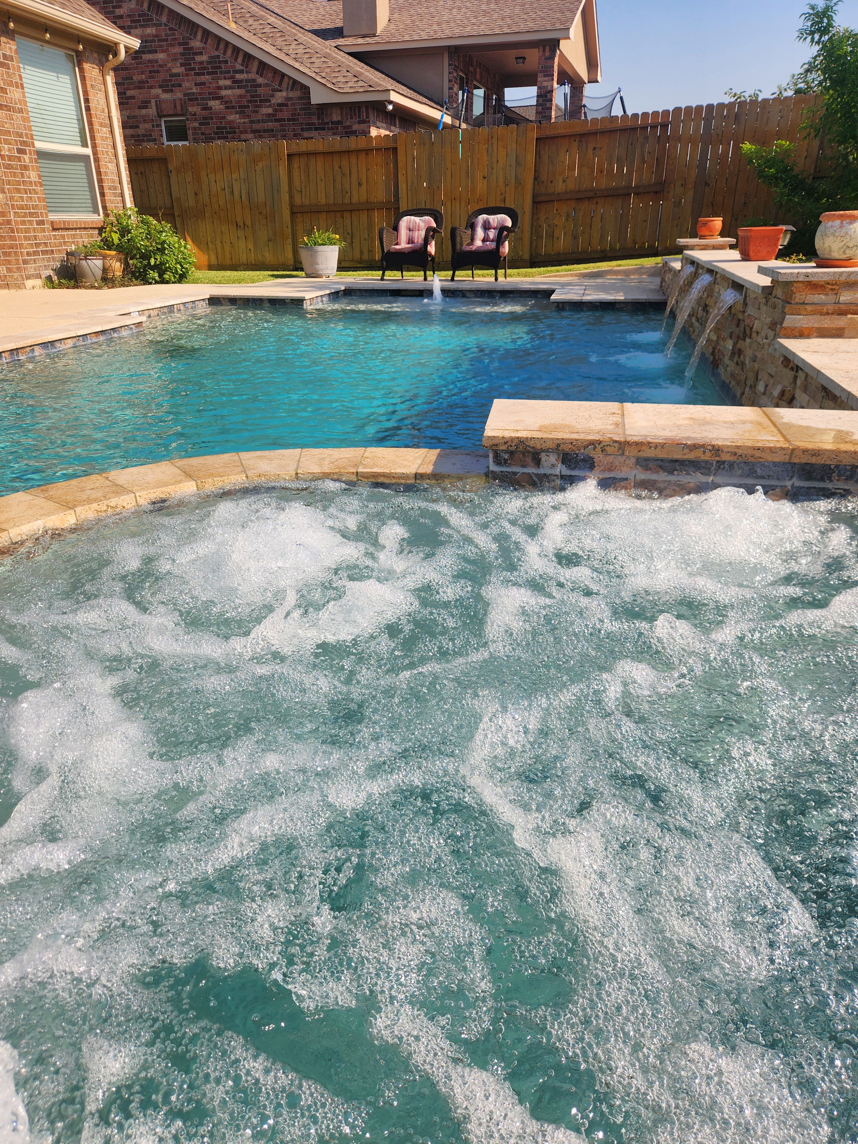 Freeform custom gunite pool with tanning ledge in a Cypress, TX backyard