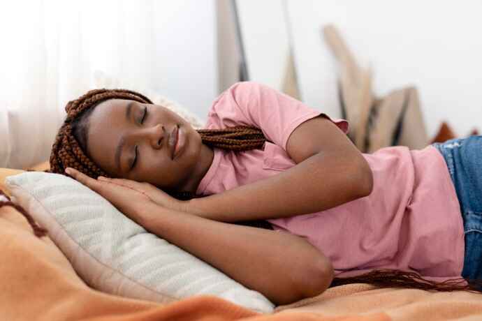 Young woman sleeping peacefully on bed, enjoying restful sleep, benefiting from hypnosis for insomnia and relaxation.