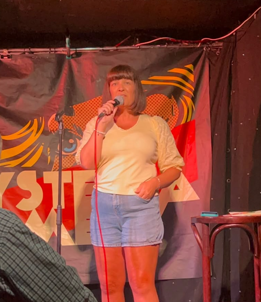 woman in a yellow top and denim shorts on a stand up stage woman in a yellow top and denim shorts on a stand up stage