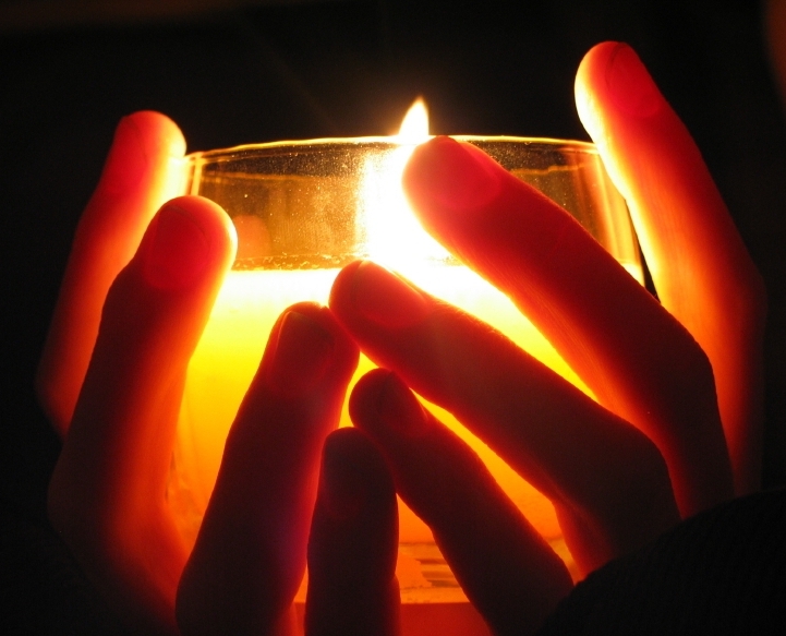 Hands cupped around candlelight
