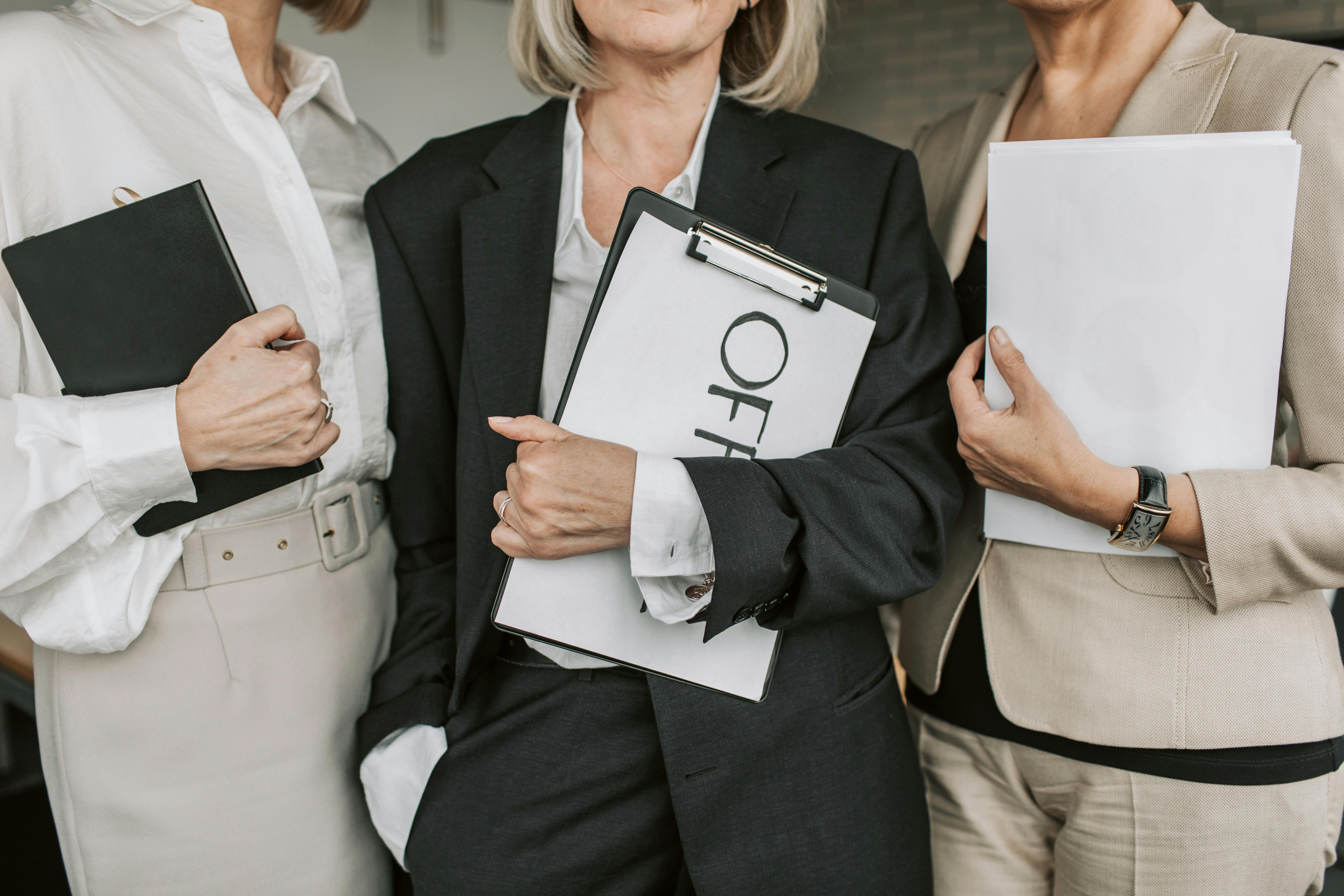 A stock image of three women holding clip boards and paper.